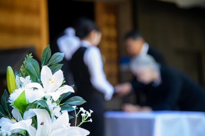 供花の奥で参列者を迎える葬儀の受付