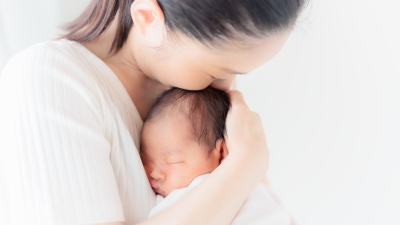 新生児を抱いて額に口づける母親