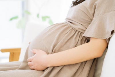 お腹に手を添えて座る妊婦